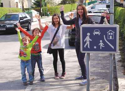 vier Kinder stehen bei einem Verkehrszeichen Wohnstraße